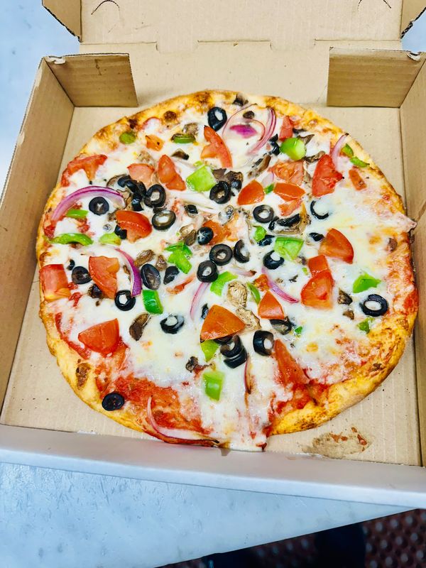 Vegetable pizza with olives, peppers, onions and tomatoes in delivery box